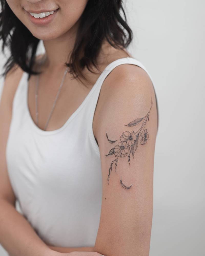 Illustrative style pansies tattooed on the upper arm.