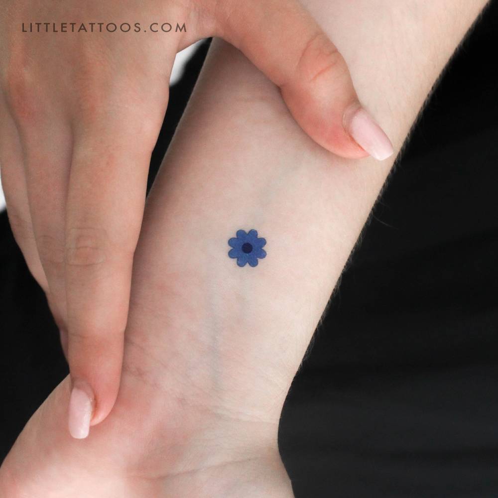 Minimalistic style little blue flower temporary tattoo placed on the wrist.
