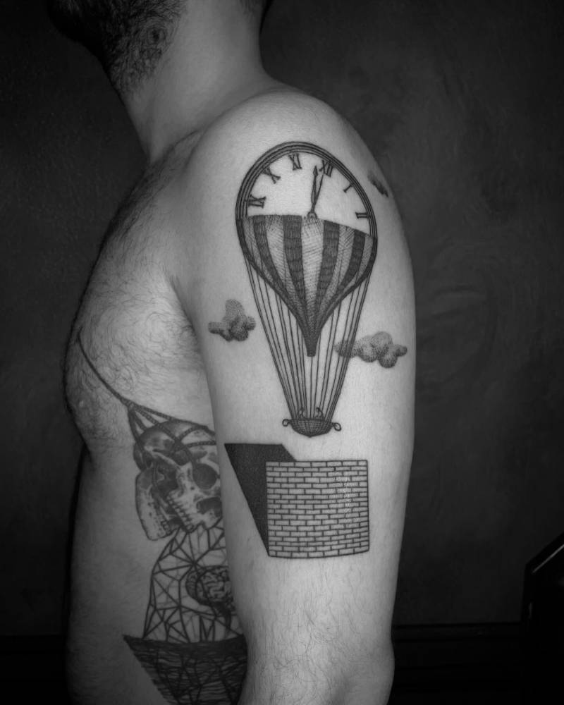 Surrealistic style hot air balloon tattoo located on the upper arm.