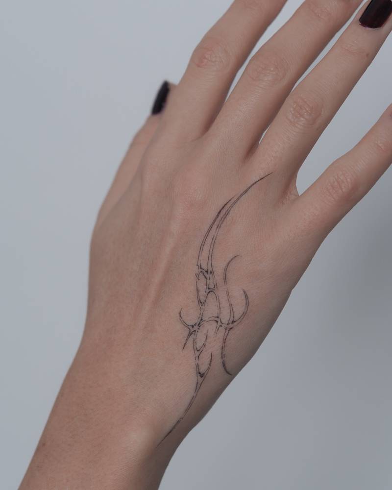 Single needle tribal design tattooed on the hand.