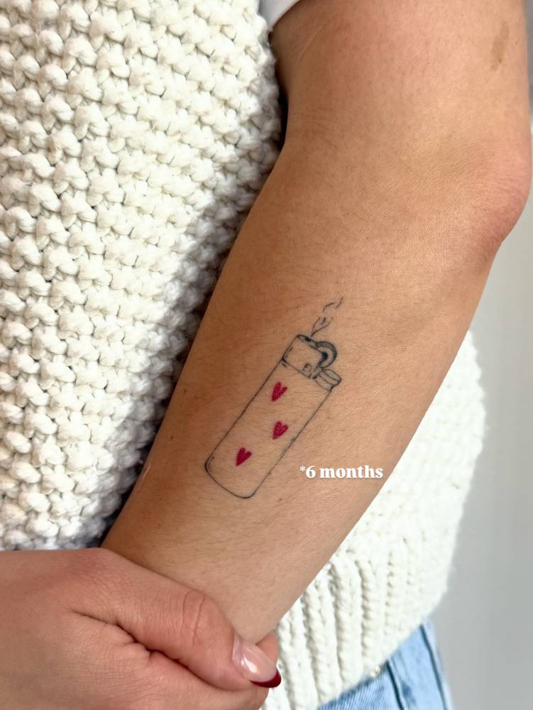 Healed lighter tattoo located on the forearm.