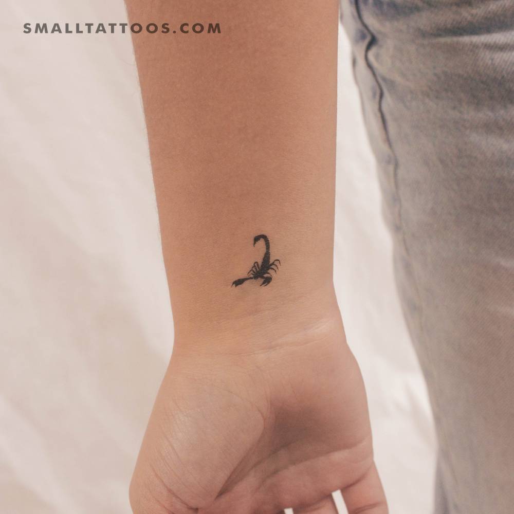 Tiny black scorpion temporary tattoo located on the wrist.