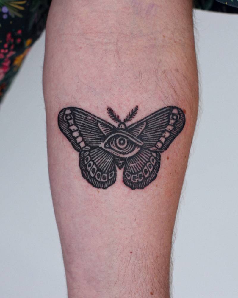 Engraving style butterfly and eye tattoo located on the inner forearm.