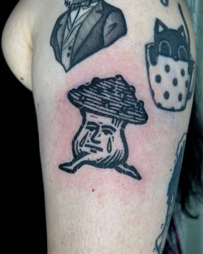 Crying mushroom tattoo in blackwork style located on the upper arm.