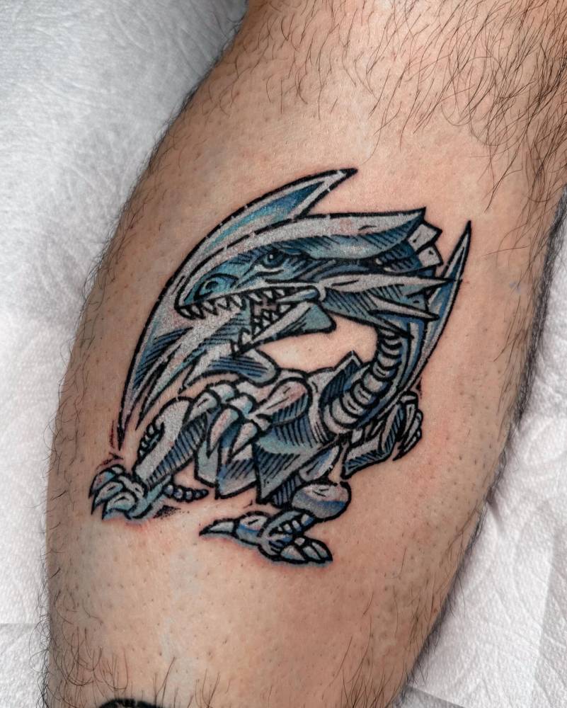 Blue-Eyes White Dragon tattoo located on the shin.