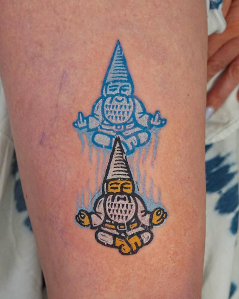 Meditating gnome tattoo in pop art style placed on the upper arm.