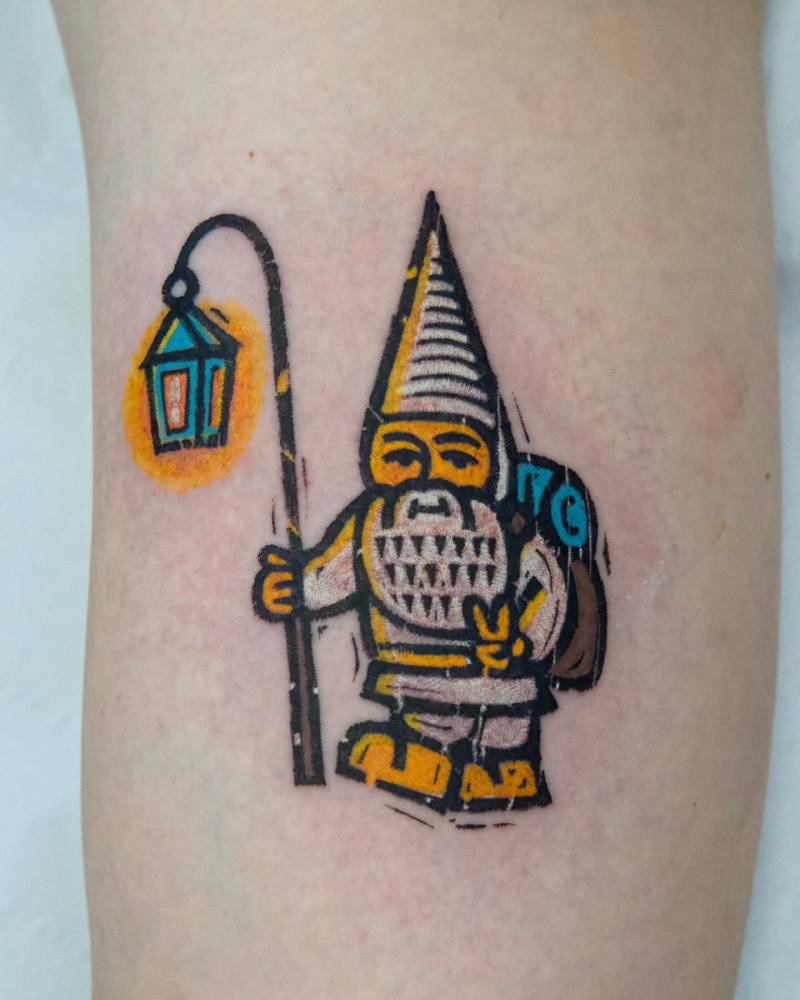 Explorer gnome tattoo located on the inner arm, done in pop art style.