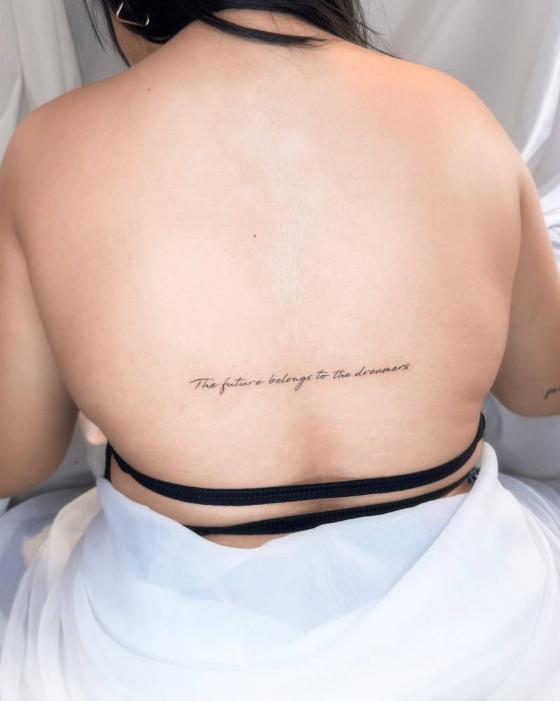 "The future belongs to the dreamers" lettering tattoo handwritten on the back.
