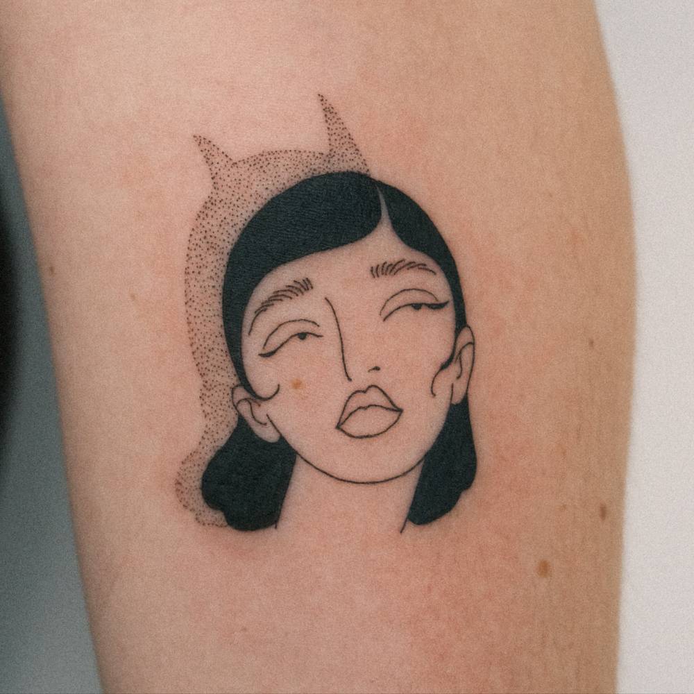Woman portrait and she-devil shadow tattoo in illustrative style located on the inner forearm.