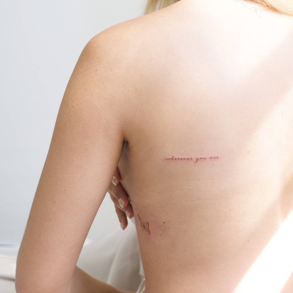 Handwritten font "wherever you are" lettering tattoo located on the shoulder blade.
