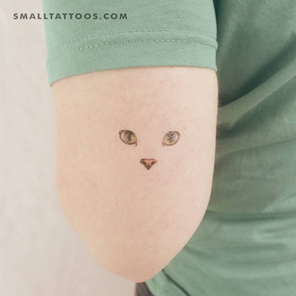 Minimalist cat face temporary tattoo located on the tricep.