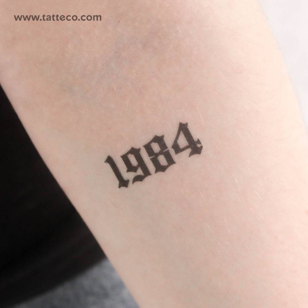 Gothic font "1984" temporary tattoo located on the inner forearm.
