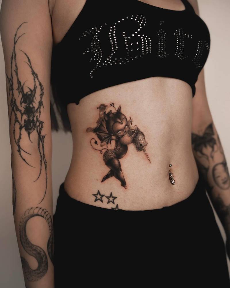 She-devil Kewpie tattoo located on the waist, cartoon style.