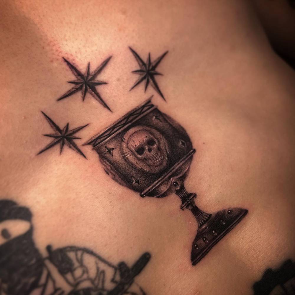 Chalice tattoo in black and grey style located on the stomach.