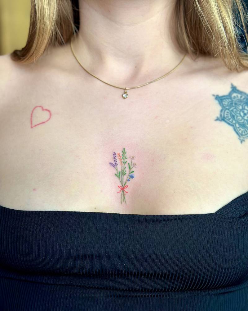 Colorful flower bouquet tattoo located on the sternum.