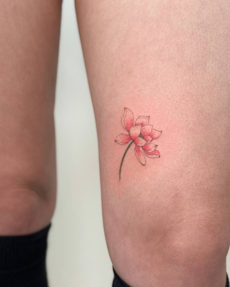 Lotus flower tattoo in watercolor style located on the thigh.