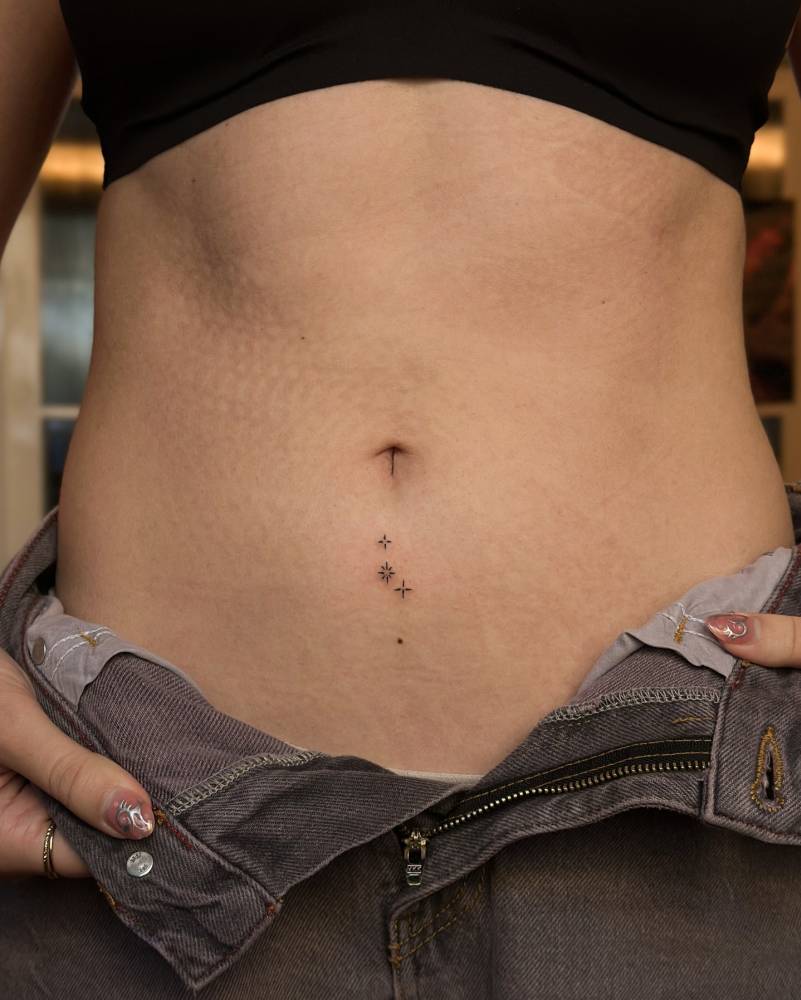 Sparkling stars tattoo in minimalistic style located on the stomach.