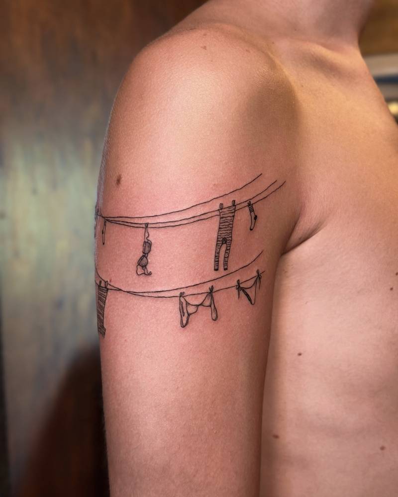 Clothes lines tattooed on the upper arm, illustrative style.