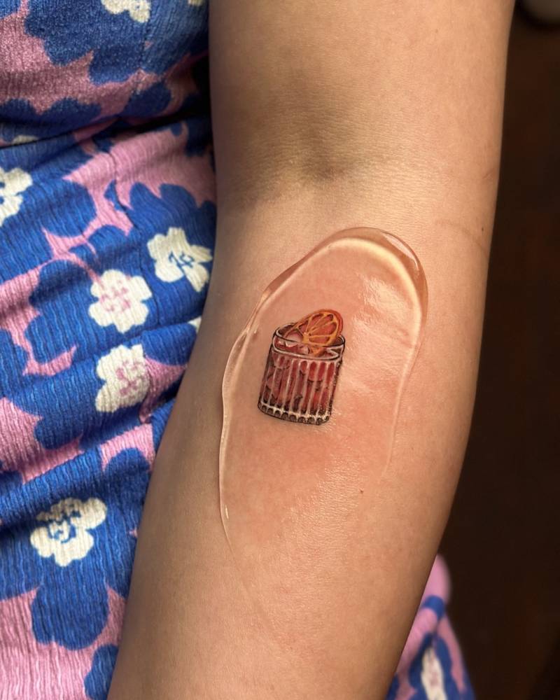 Negroni cocktail tattooed on the forearm, illustrative style.