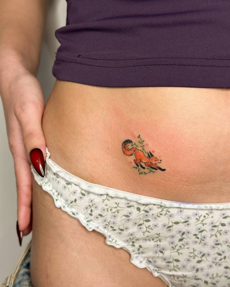 Watercolor style little fox tattoo located on the pelvis.