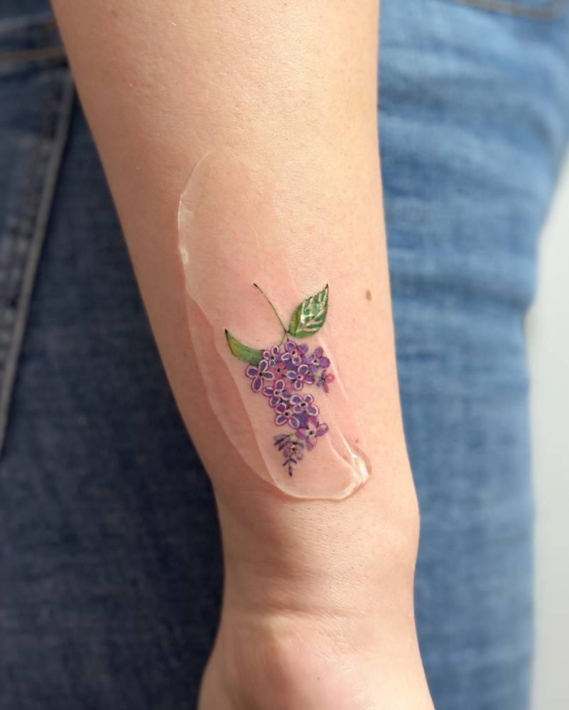 Lilac flowers tattoo in watercolor style placed on the wrist.