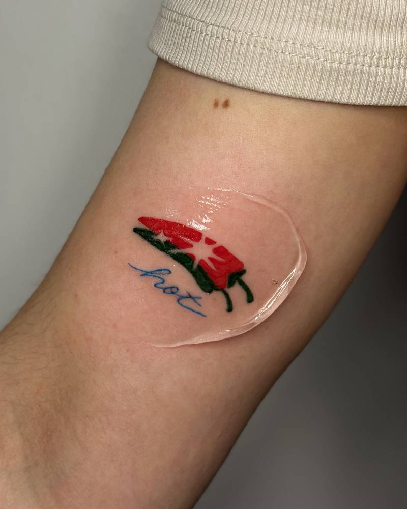 Red chili and word "hot" tattooed on the inner arm, illustrative style.