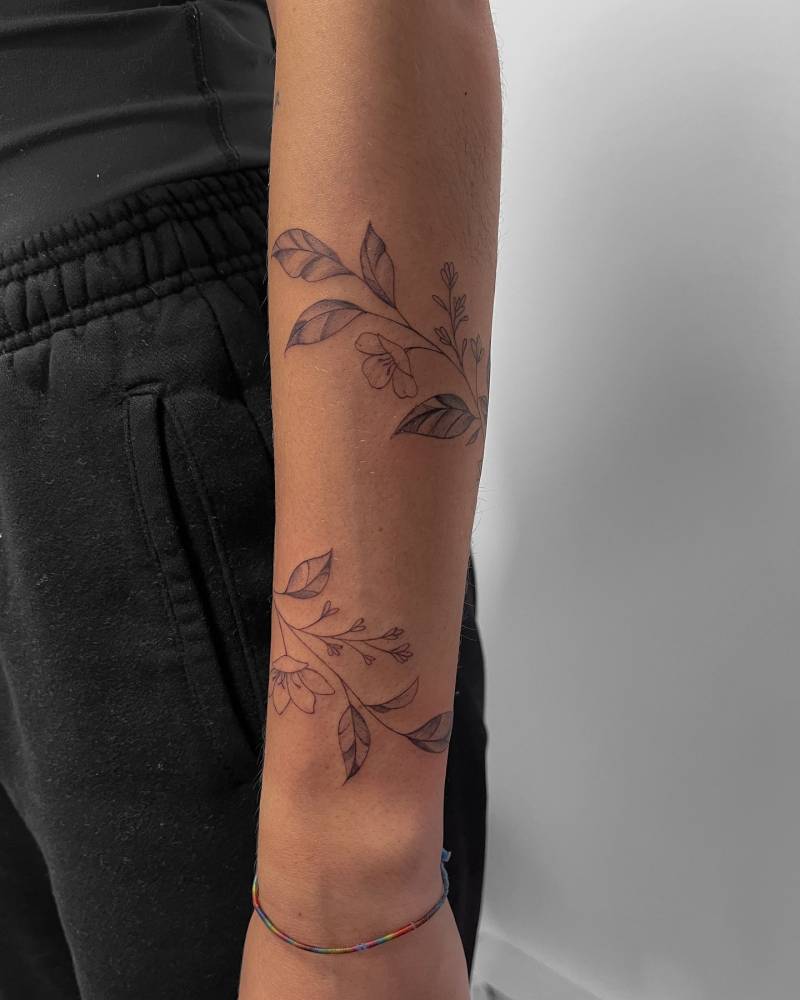 Flower bracelet tattoo in illustrative style located on the forearm.