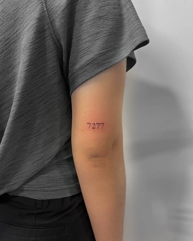 Tattoo of the number "7277" in serif font located on the tricep.