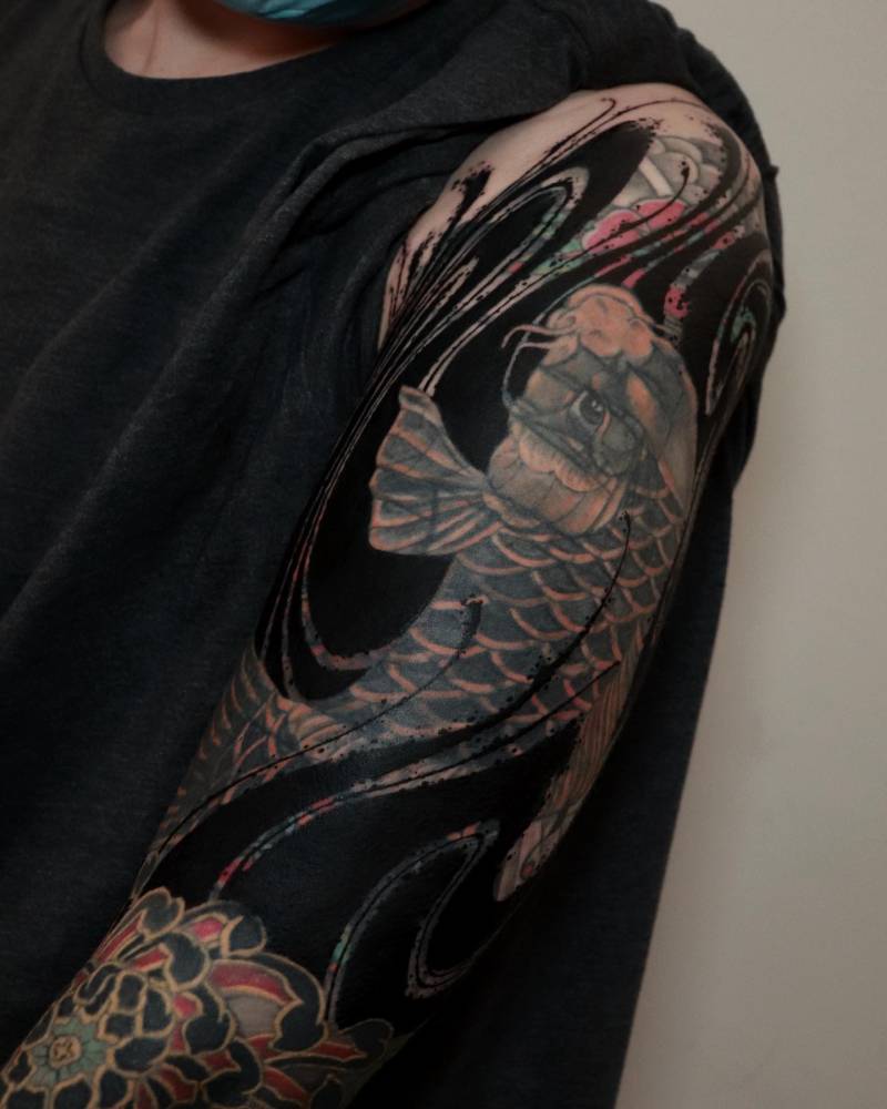 Flow cover up tattoo in blackwork style located on the upper arm.