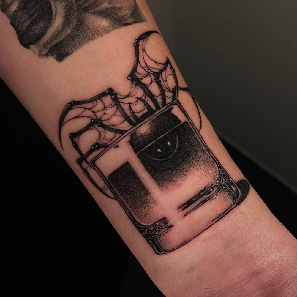 Spider in a glass tattooed on the wrist, blackwork style.