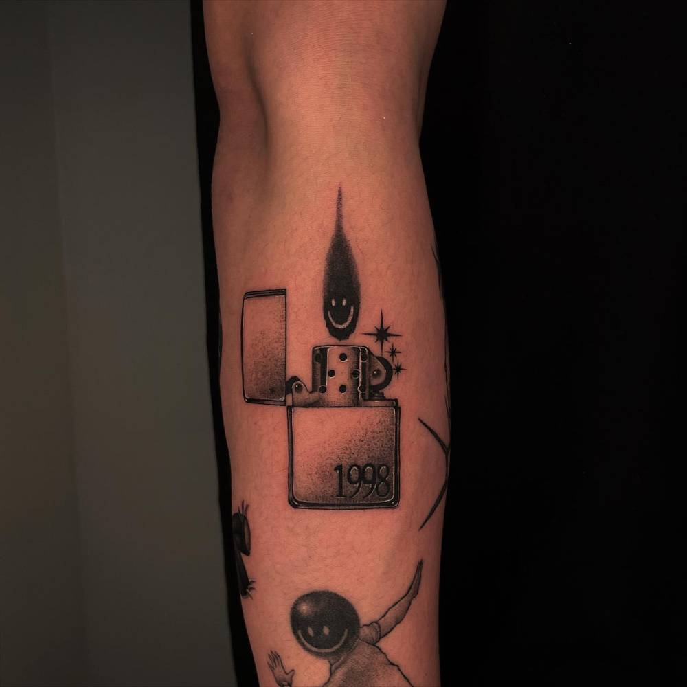 Blackwork style lighter tattoo located on the forearm.