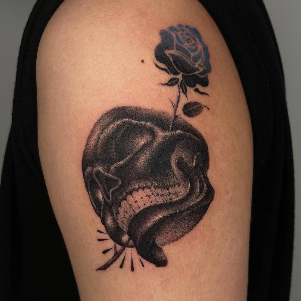 Dotwork style skull and rose tattoo placed on the upper arm.