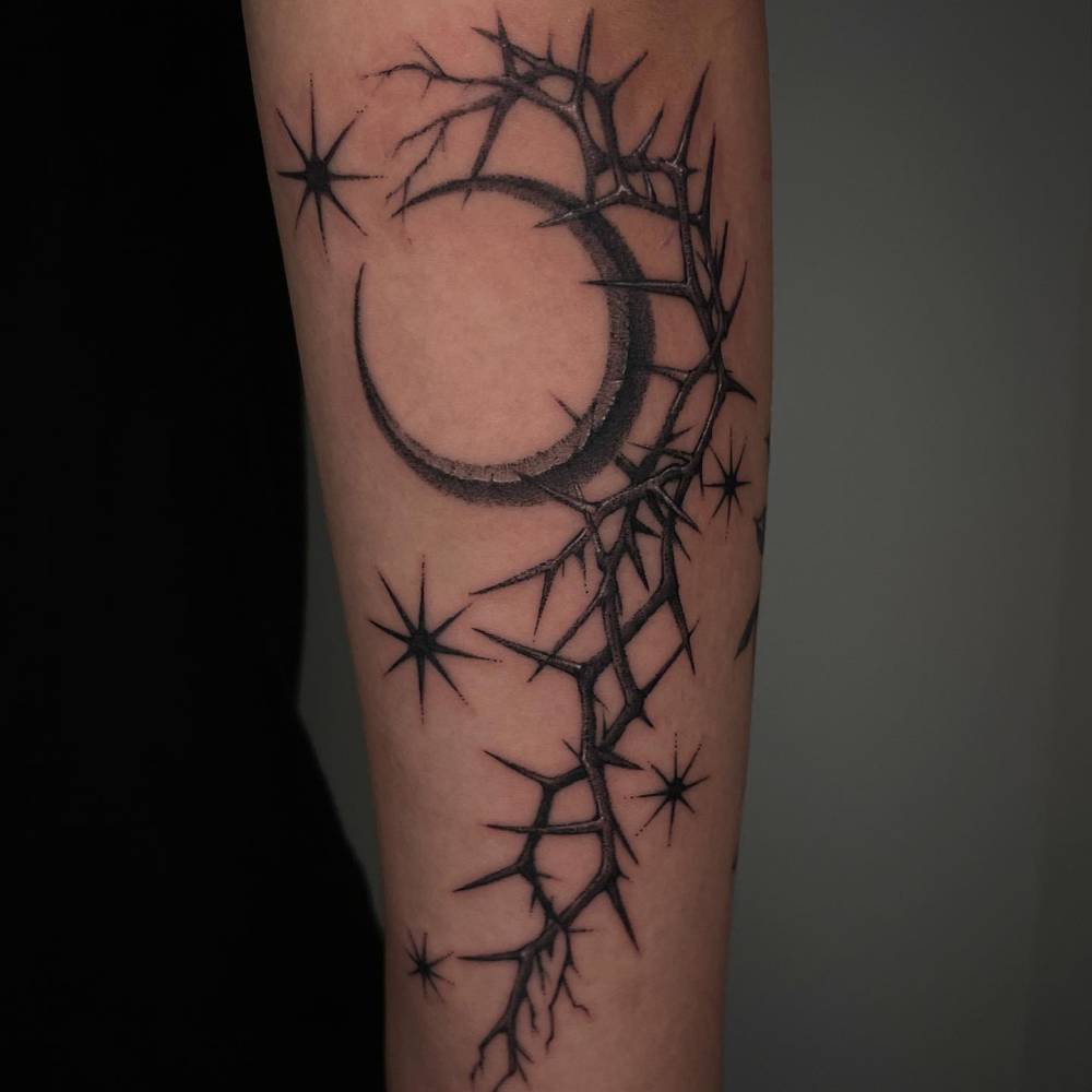 Blackwork style crescent moon and thorns tattoo located on the forearm.