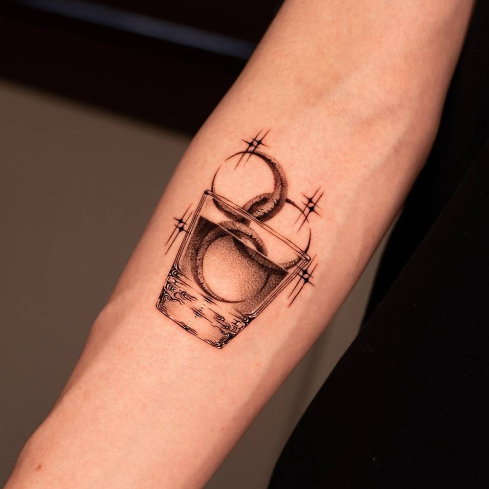 Glass filled with moons tattooed on the inner forearm.