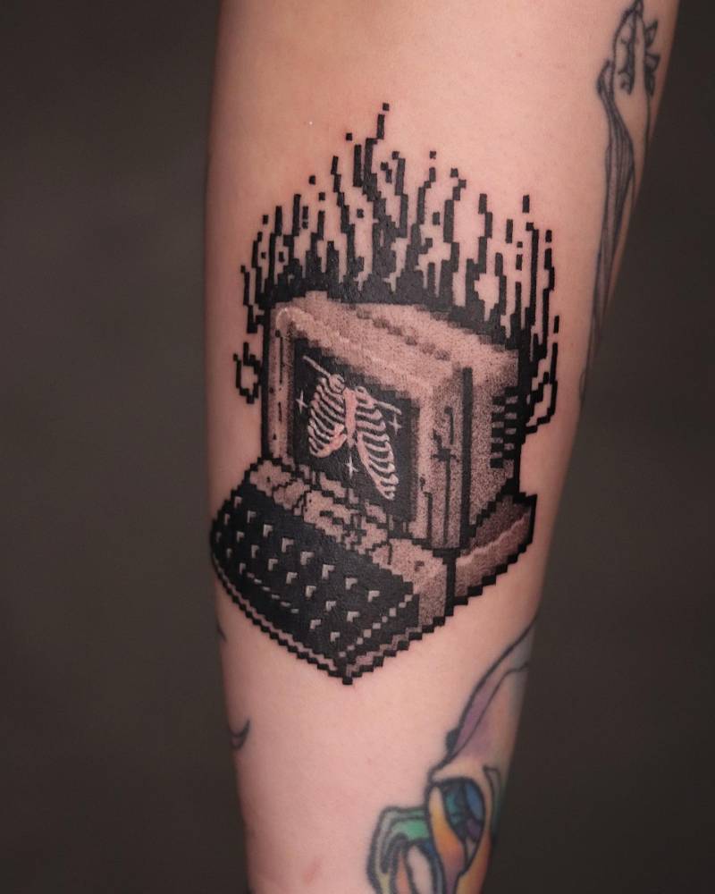 Pixelated computer tattooed on the inner forearm, blackwork style.