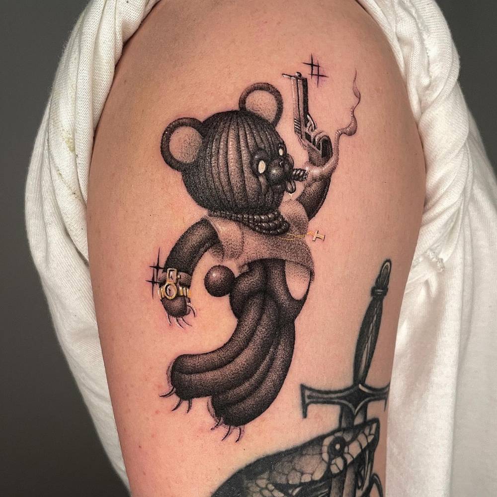 Dotwork style thug teddy bear tattoo located on the upper arm.