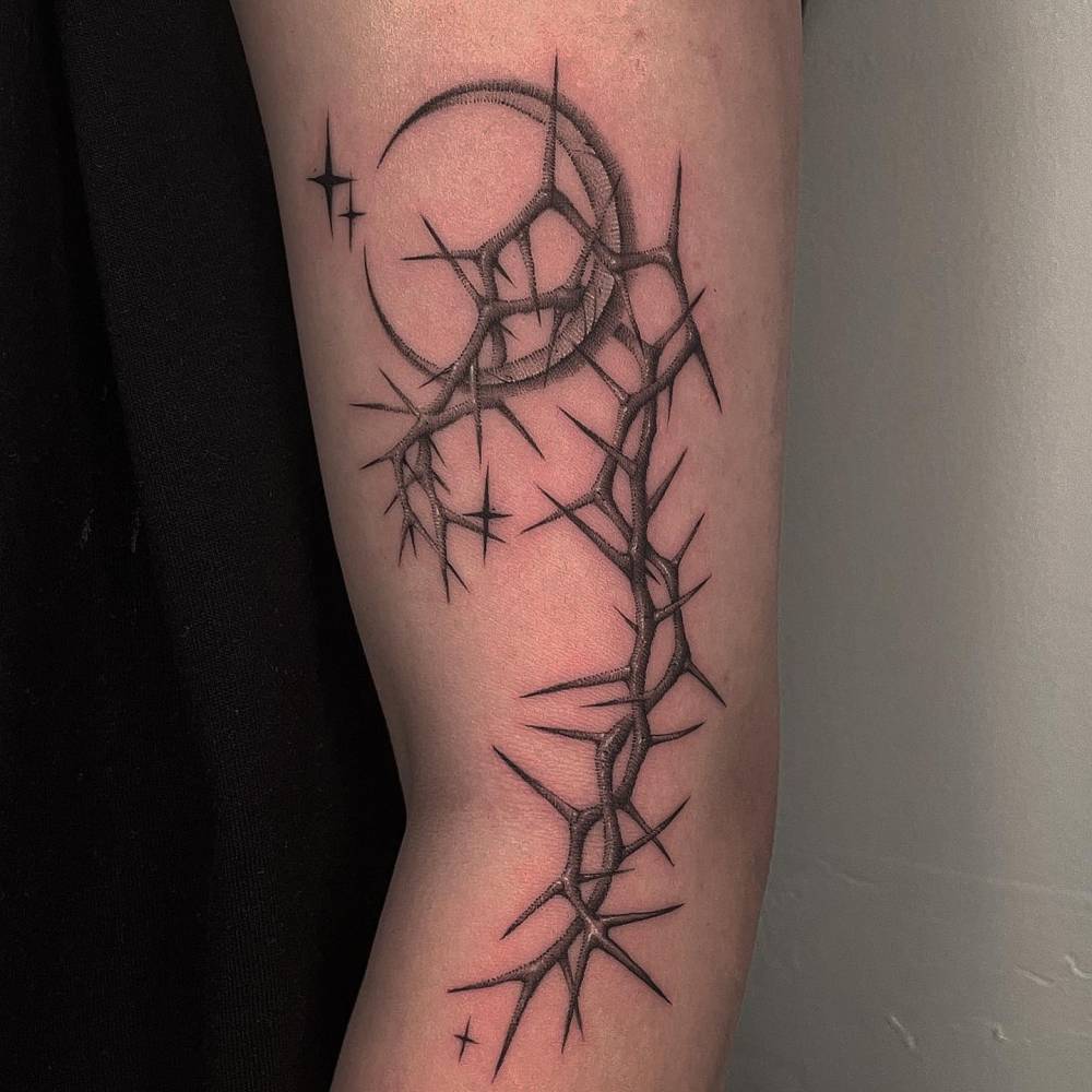 Crescent moon and thorns tattoo located on the arm.