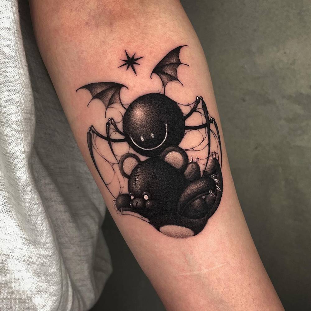 Smiley spider and teddy bear tattoo in dotwork style located on the inner forearm.