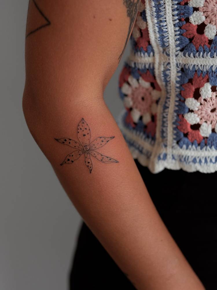 Illustrative style orchid tattoo located on the forearm.