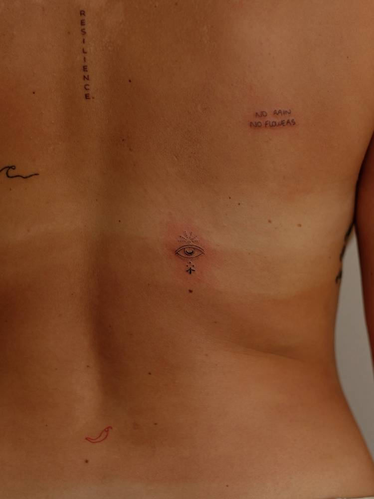 Ornamental eye tattoo in fine line style located on the back.