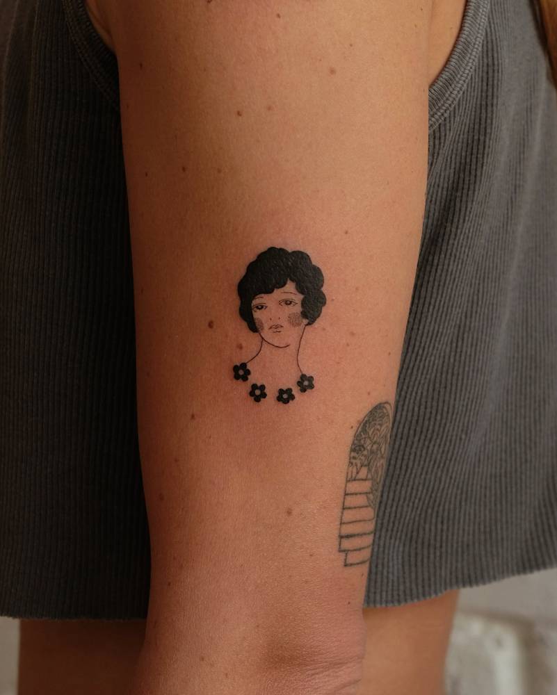 Woman portrait tattoo in blackwork style located on the upper arm.