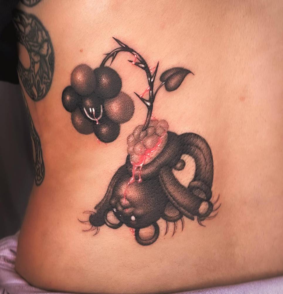 Dotwork style daisy flower and teddy bear tattoo located on the lower back.
