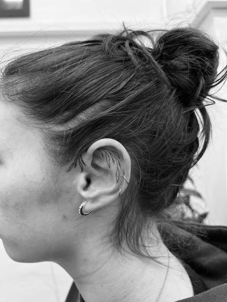 Fine line style leaves tattoo located on the ear.