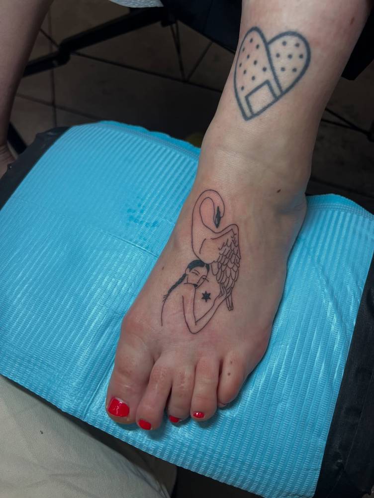 Woman and swan tattoo located on the foot, done in illustrative style.