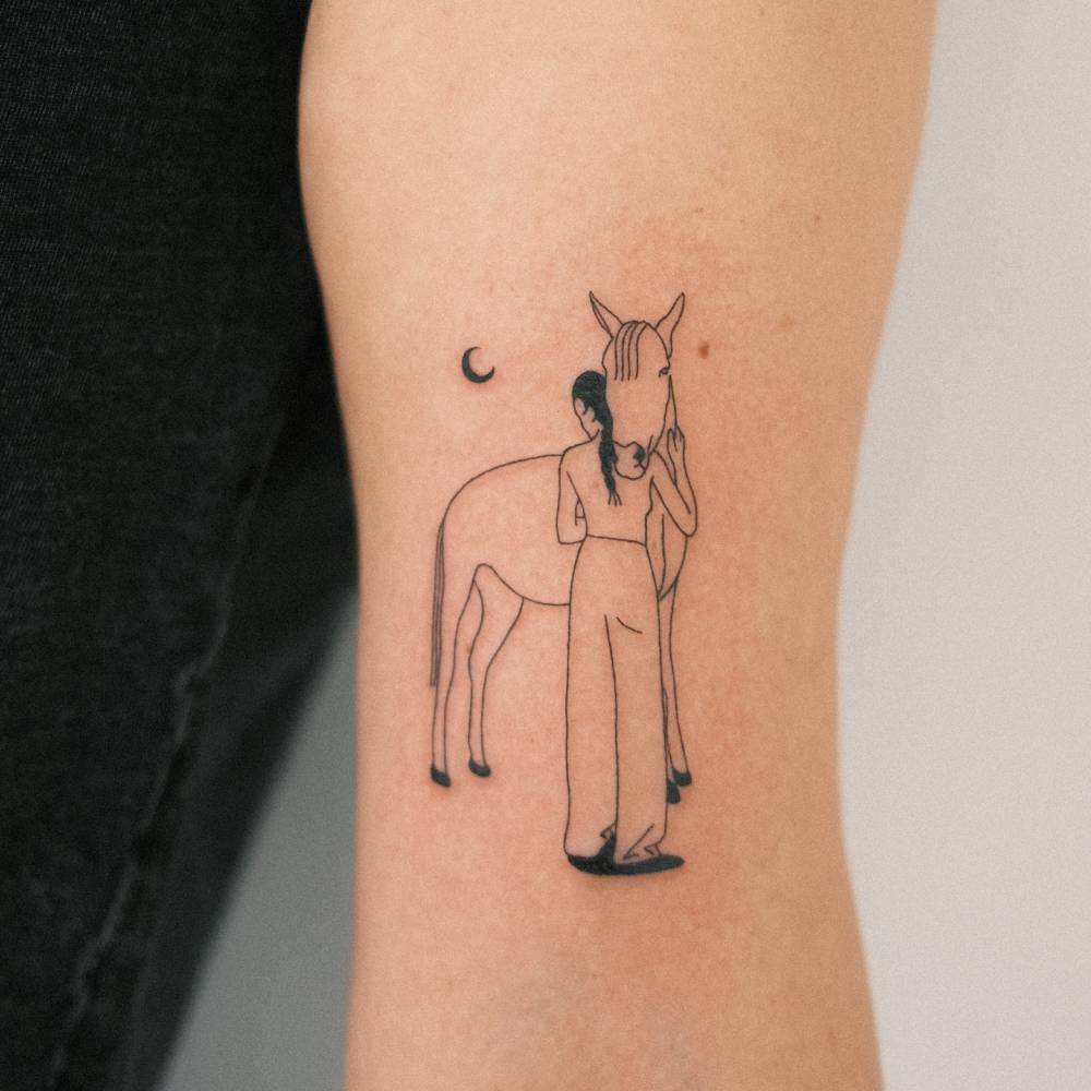 Woman and horse tattoo located on the bicep, illustrative style.