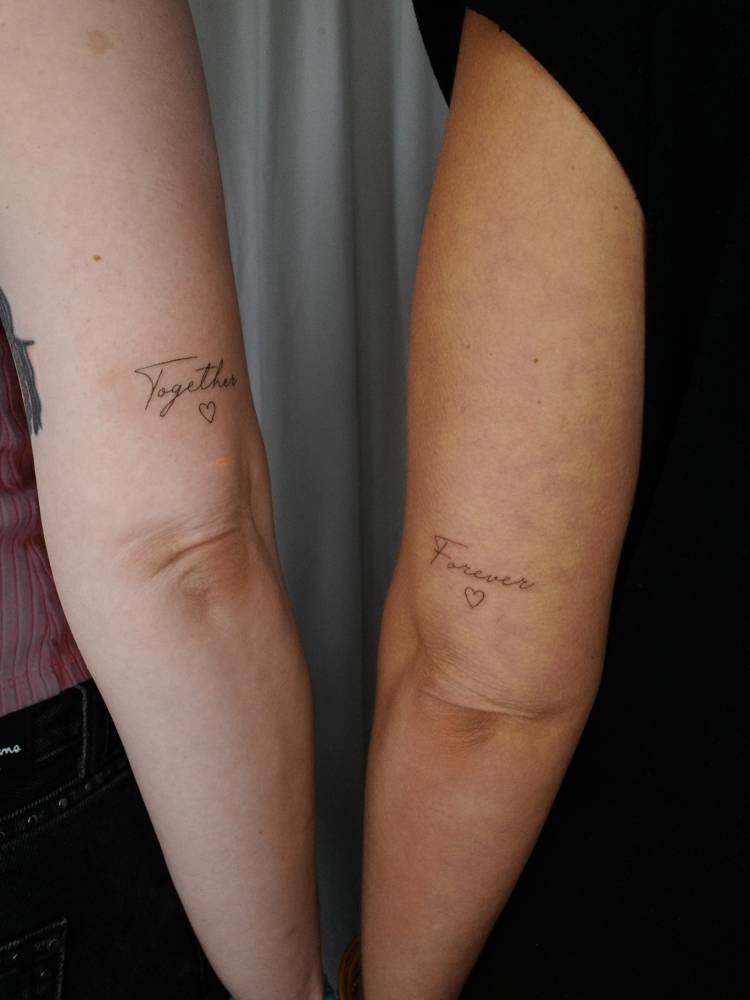 Matching "together" and "forever" lettering tattoo for mother and daughter.