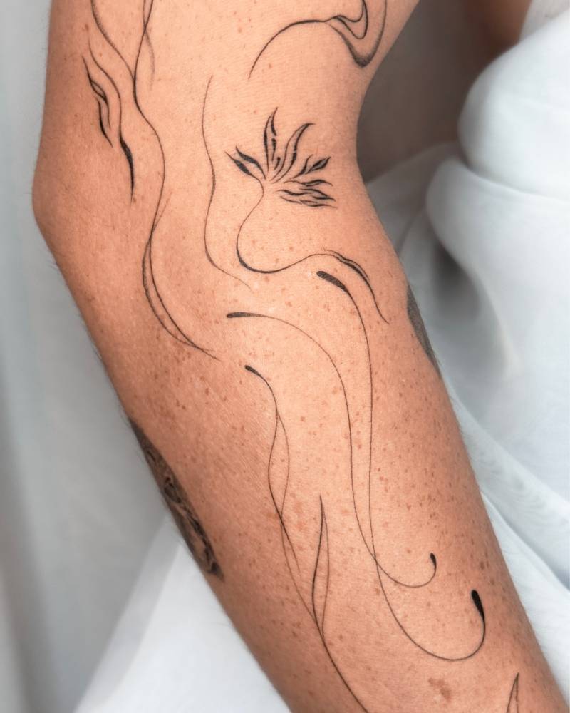 Abstract style flower tattoo located on the arm.