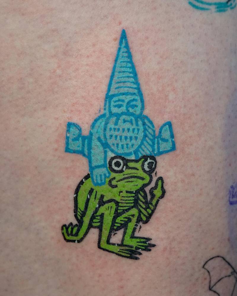 Pop art style gnome and frog tattoo located on the thigh.