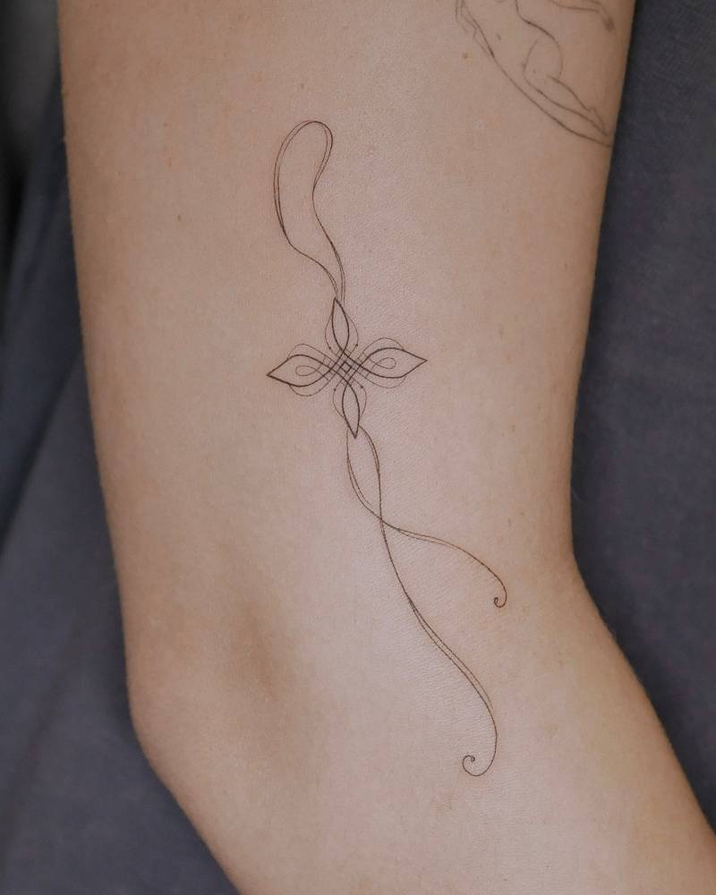 Fine line style ornamental tattoo located on the upper arm.