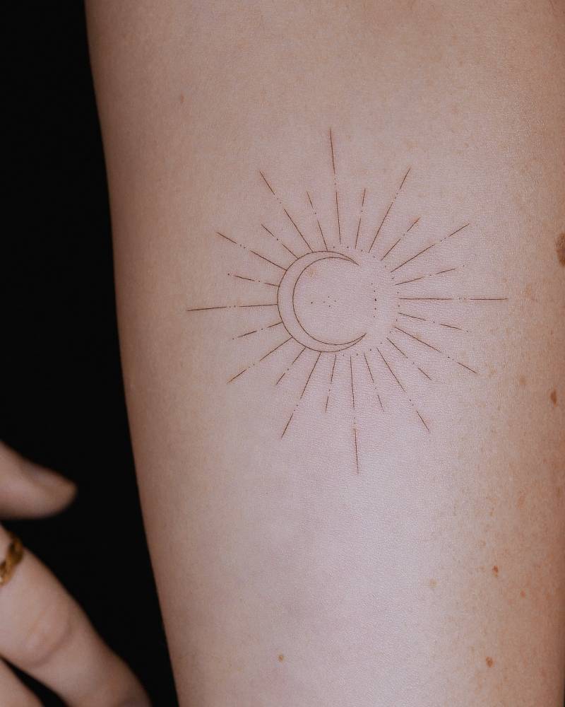 Sun and moon tattoo in fine line style located on the inner forearm.